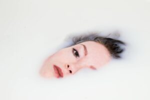 A serene portrait of a woman submerged in a milk bath highlighting relaxation and beauty.