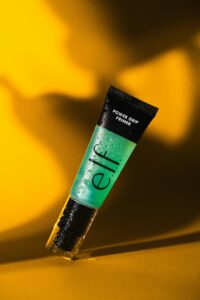 Energizing image of a cosmetic primer with bold lighting and water droplets.