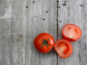 Close-up of ripe tomatoes on a rustic wooden table with peppercorns.